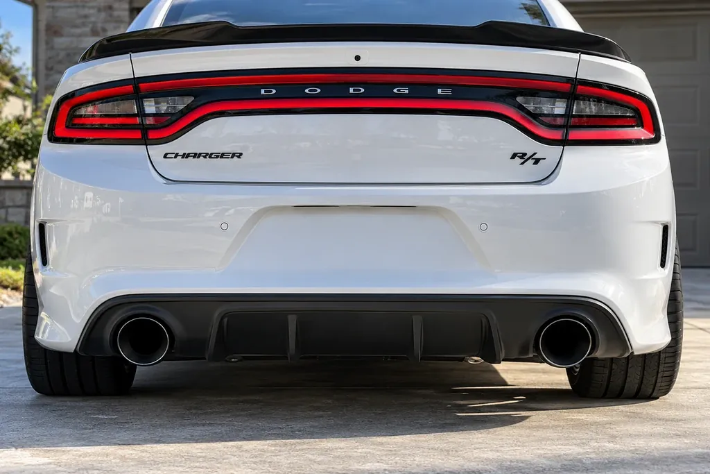 Rear bumper of a white Dodge Charger R/T with black 5-inch exhaust tips in the round bumper openings