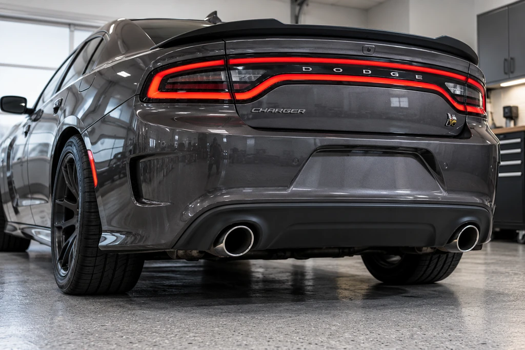 Rear of a dark grey Dodge Charger Scat Pack with the factory exhaust tips in the lower valance